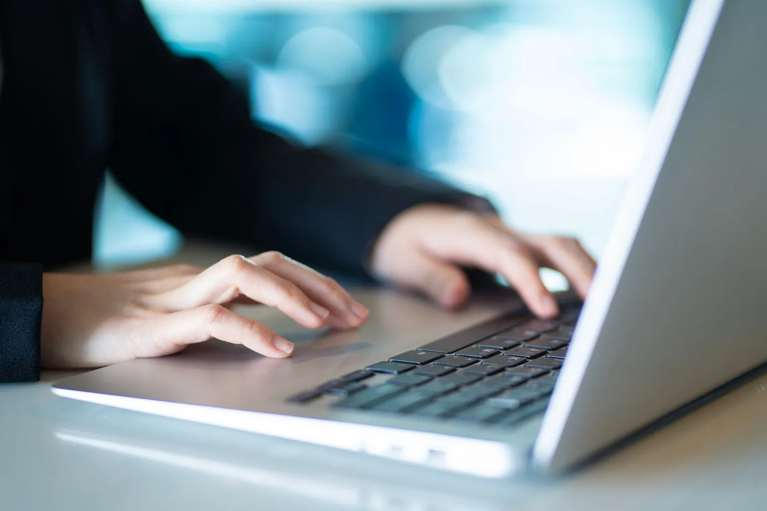 Mains posées sur le clavier et le pavé tactile d’un ordinateur portable gris