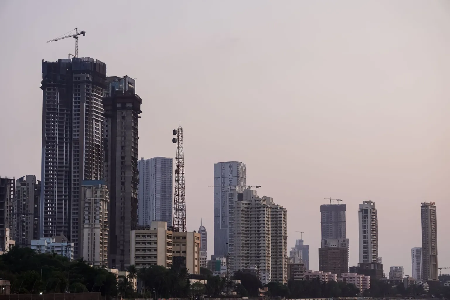 Tours résidentielles et grues de chantier se découpant sur le ciel du soir à Mumbai