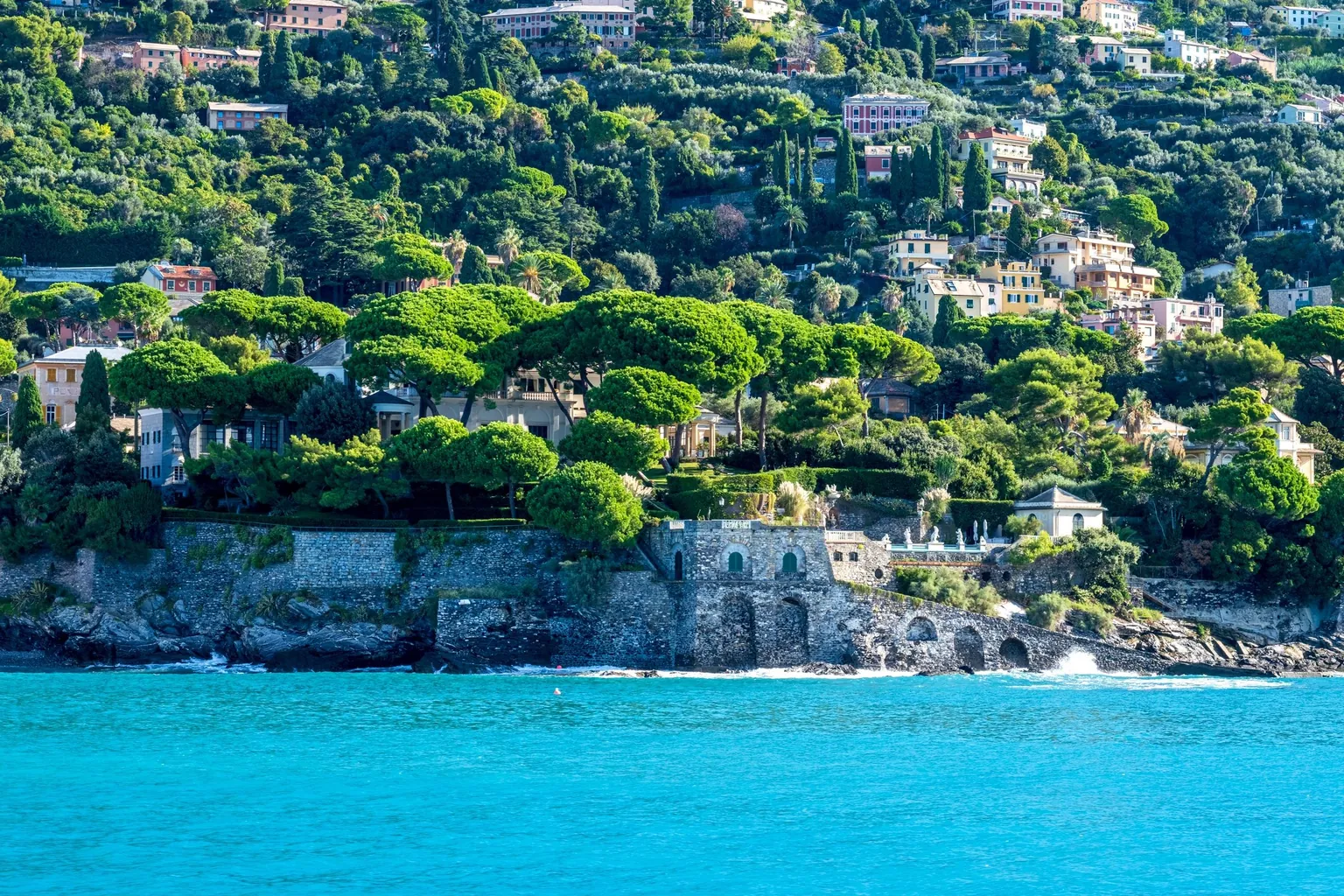Villas nichées sous les pins parasols au-dessus d'une mer turquoise, sur une côte méditerranéenne