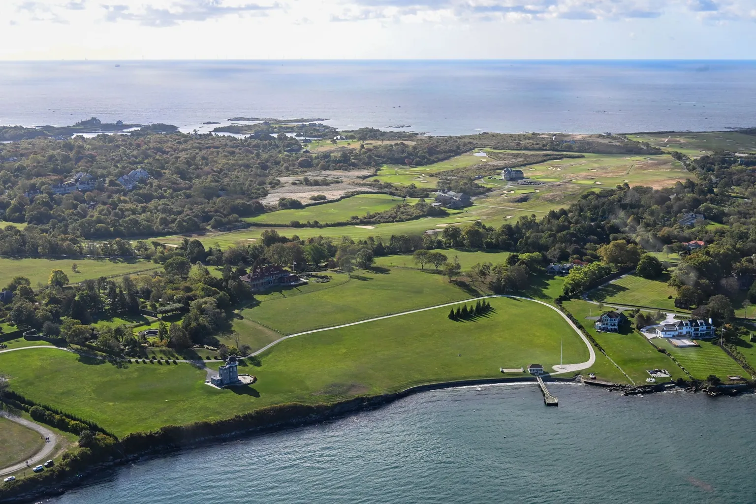 Vue aérienne de grandes propriétés en bord de mer, entourées de pelouses, de bois et d'un golf face à l'océan