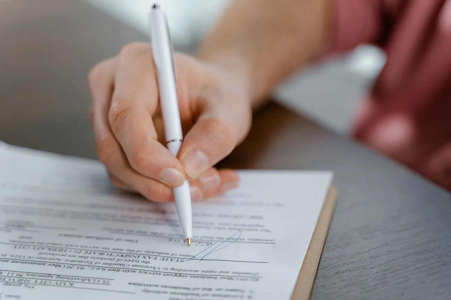 Main signant un formulaire officiel au stylo sur une planchette