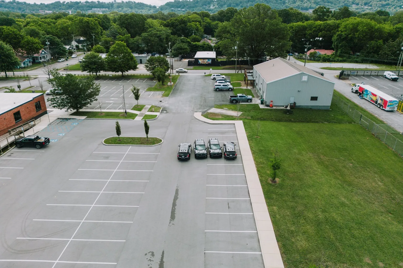 Parking en plein air vu du ciel, avec ses places tracées au sol en grande partie libres et quelques voitures garées